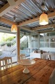 White china dish on wooden table in front of glass wall with view of garden below corrugated metal ceiling