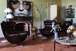 Leather bucket armchair, antique globes and vintage lamps in living room with fireplace