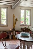Dining area with retro chair and large vintage clock hands on bench in rustic, country-house interior