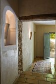 Illuminated niche in hallway of restored Provençal building with rug on tiled floor