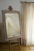 Dressing mirror in old cabinet top frame on painters' easel in Provençal bedroom