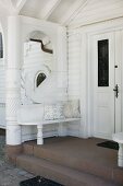 Bench integrated into porch of grand residence with white wooden façade