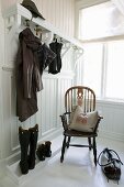 Windsor chair with scatter cushion in white-panelled cloakroom; high boots, raincoat and umbrella