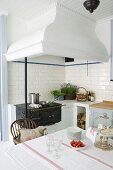 Masonry mantel hood above antique cooker in kitchen-dining room