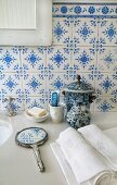 Traditional, blue and white tiles, hand mirror and ceramic pot on stone washstand counter