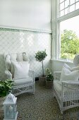 White wicker chairs with pale cushions in conservatory with tiled dado