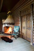 Fire in artistic, masonry, corner fireplace made from pale and brown decorative bricks in rustic, log-cabin-style interior
