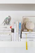 Books and ornaments on white wall-mounted shelf