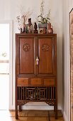 Antique Oriental cabinet decorated with collectors' items, vases and potted plants