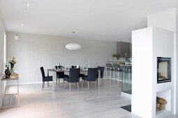 Open-plan minimalist interior with black upholstered chairs and masonry fireplace