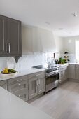 Kitchen counter with white worksurface and grey-painted base units in spacious kitchen