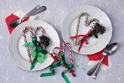 Candy canes arranged in love-hearts decorated with ribbon and sprigs of berries as festive table decorations