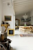 Designer Enigma pendant lamp above dining set with classic chairs; antique, Rococo, gilt console table to one side in open-plan interior