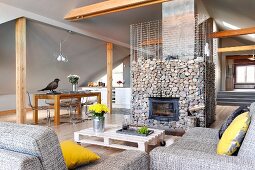 Yellow scatter cushion on grey marl sofa and low coffee table in front of fireplace in gabion cage in converted attic with pale grey walls