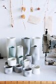 Handgefertigte Keramikvasen neben Nähmaschine auf Werkbank