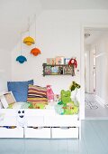 White children's bed with drawers and colourful pendant lamps hanging from the sloping wall