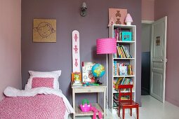Girl's bedroom with mauve-painted walls, open-fronted shelves and pink standard lamp