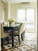 Dining table and chairs with pale, mottled upholstery on animal-skin patchwork rug with traditional pattern