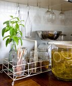 Retro glassware in white wire basket next to glass jar of elderflower syrup