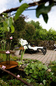 Sun loungers on paved terrace with gabion wall in garden