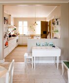 View from dining area into open-plan, rustic kitchen with white folding table against half-height partition