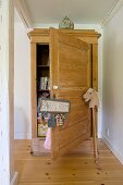 Pale wooden farmhouse cupboard with open door, sign hanging from doorknob and hobby horse to one side