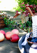 Red apples and crockery on rustic table outdoors