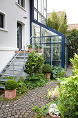 House with metal exterior steps, conservatory and garden path paved in fantail pattern