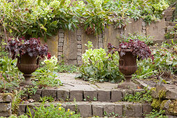 Planted urns in front of stone wall