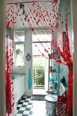 Blick durch drapierten, roten Perlenvorhang in winzige Küche mit Balkon