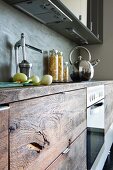 Rustikaler Küchenunterschrank mit Holzfront; verchromter Wasserkessel und Orangenpresse auf der Arbeitsfläche