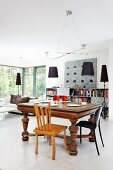 Lamps with black lampshades in open-plan interior with central dining area in eclectic mixture of styles