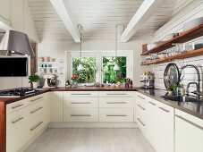 Moderne weiße Einbauküche in renoviertem Landhaus mit Holz-Geschirrboards, Küchentheke und sichtbaren weißen Balken