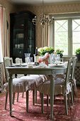Antique dining table an chairs with ruffled cushions in rustic dining room