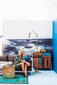 Young woman sitting in front of photo mural of the sea in eclectic maritime interior