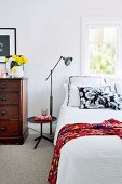 Vintage chest of drawers and standard lamps in bright, vintage-style bedroom with carpet in period apartment