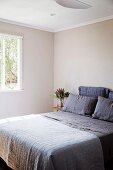 Simple, minimalist bedroom with beige walls and purple bed linen
