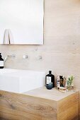 Elegant wooden washstand with white sink against wood-clad wall