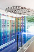 Indoor pool with colourful graphic wall mosaic and lights in metal frame