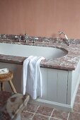 Badewanne mit Marmor Einfassung und hellgrau lackierte Holzfront