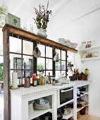 White kitchen counter against partition with lattice windows in simple wooden house