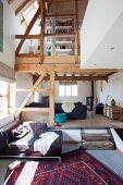Open-plan living area in renovated farmhouse with gallery and rustic timber frame