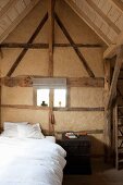 Restored, half-timbered wall with gable-end window in vintage-style bedroom