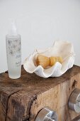 Shaving brush in white seashell and spray bottle on rustic wooden block with tap handles