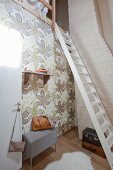 High cubby bed above wall with floral wallpaper, white-painted ladder and white, masonry chimney in modernised farmhouse
