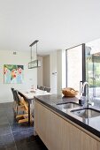 Kücheninsel mit Stein-Arbeitsplatte, dahinter Esstisch in modernem, offenem Wohnraum