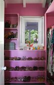 Walk-in wardrobe painted pink with integrated shoe rack and handbag shelf