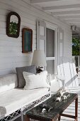 Finds on table with woven textile top and delicate bamboo bench on white wooden veranda