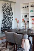 Row of vases holding protea flowers on dark wooden dining table with light grey upholstered chairs