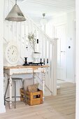 Wandtisch mit abblätternder Farbe vor Treppenlauf mit weißem Holzgeländer in Diele